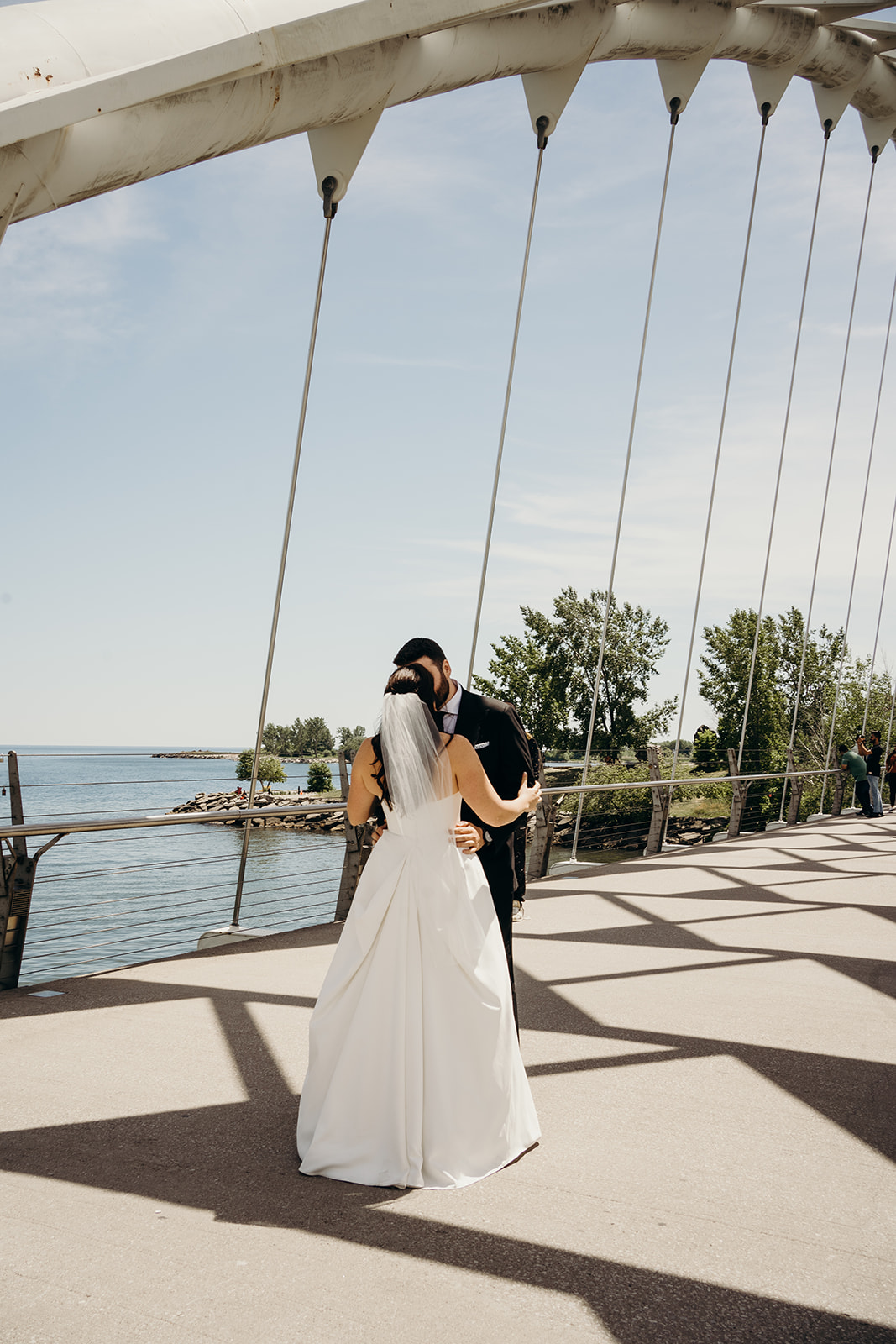 woman facing the man on a bridge by the lake outside.