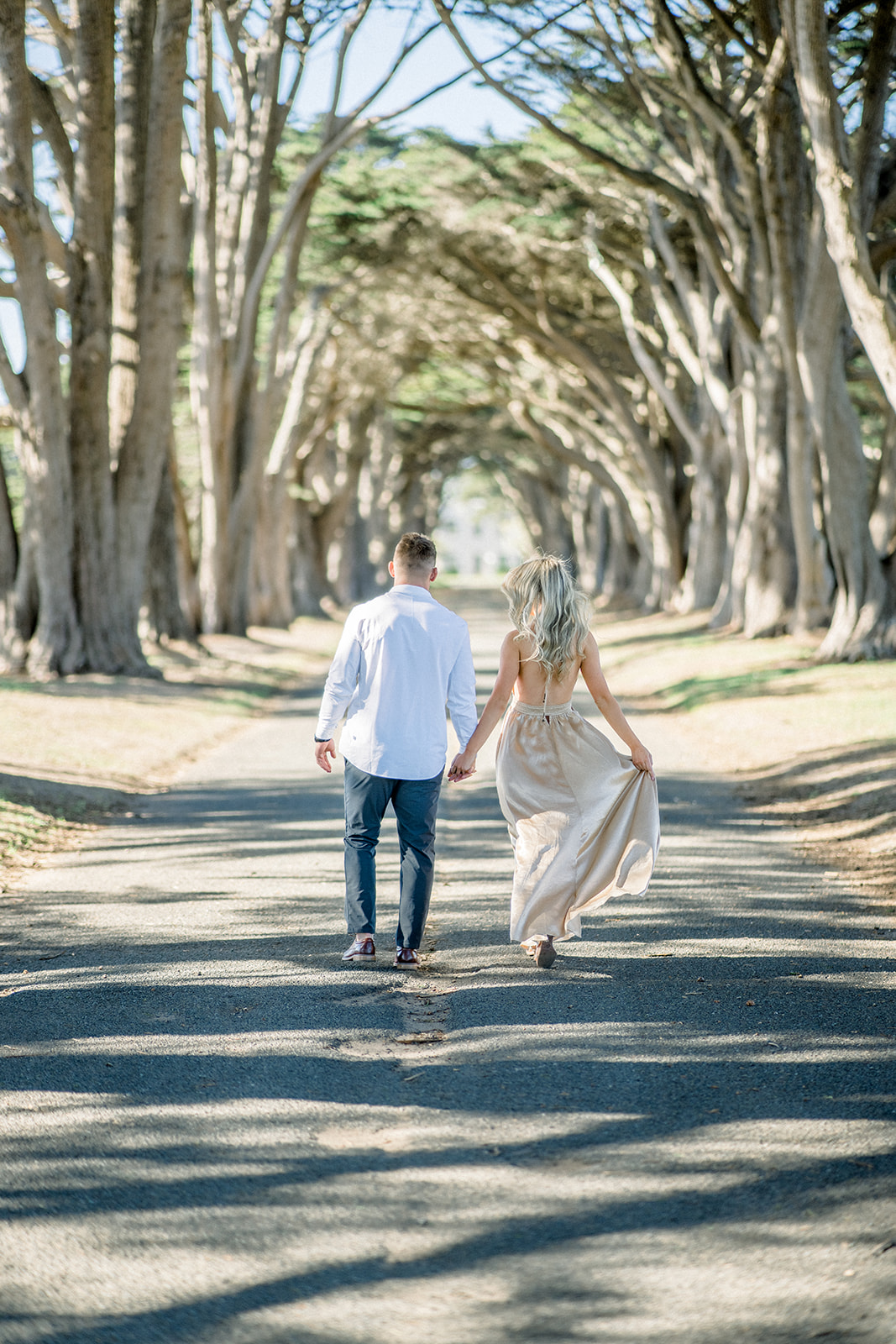 Engagement couple walking away at Cypress tree tunnel at Point Reyes CA