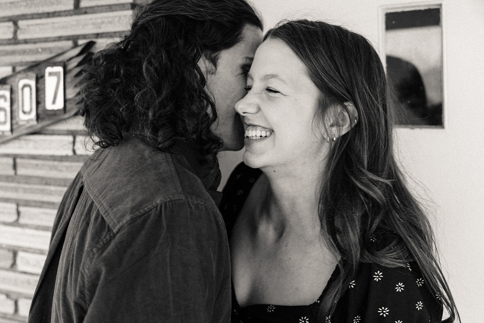 woman smiling while her fiance kisses her cheek 