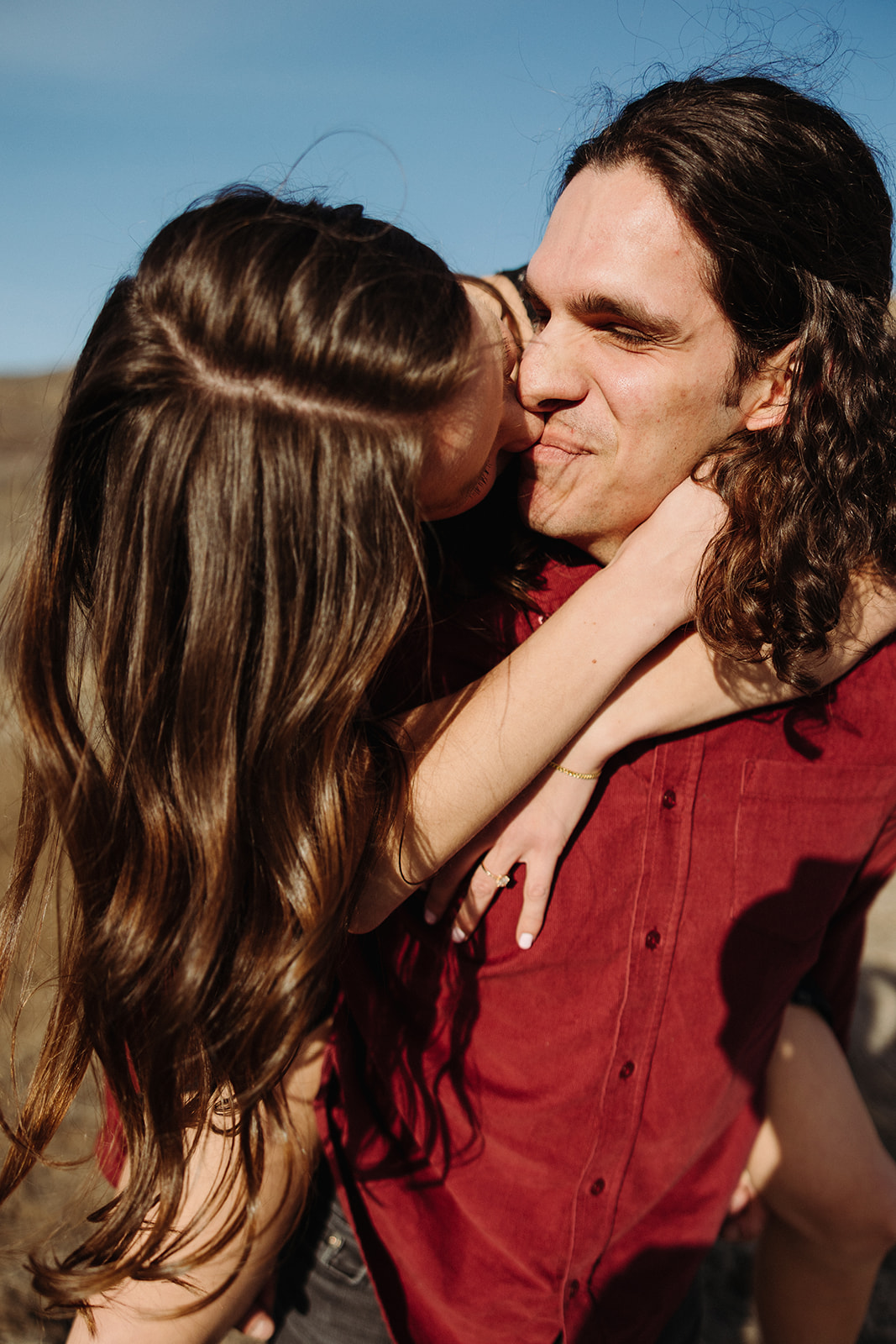 man smiling while his fiance kisses her cheek 
