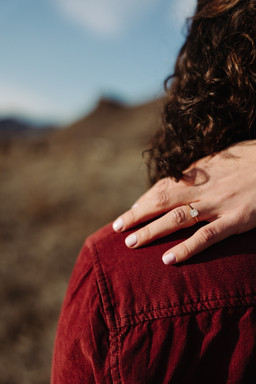 woman's hand resting on a man's shoulder showing her engagement ring