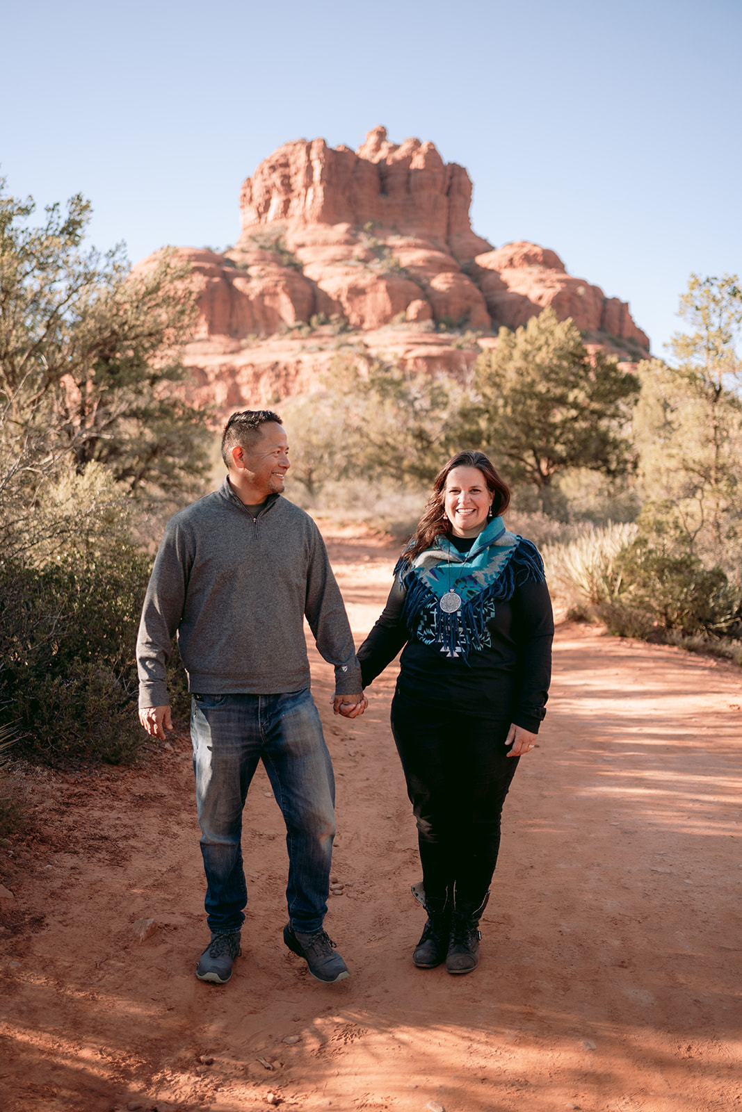 couple walks in front of Sedona red rocks