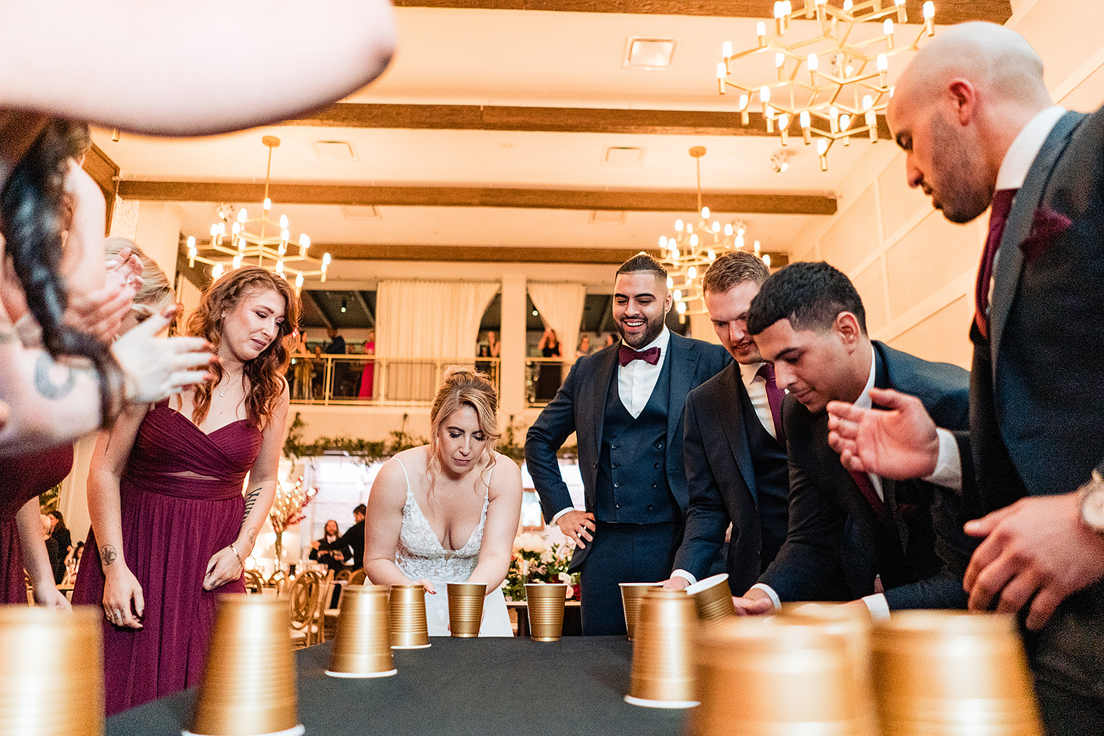 Bridal party playing flip cup at a wedding reception by Cescaphe the Lucy. 
