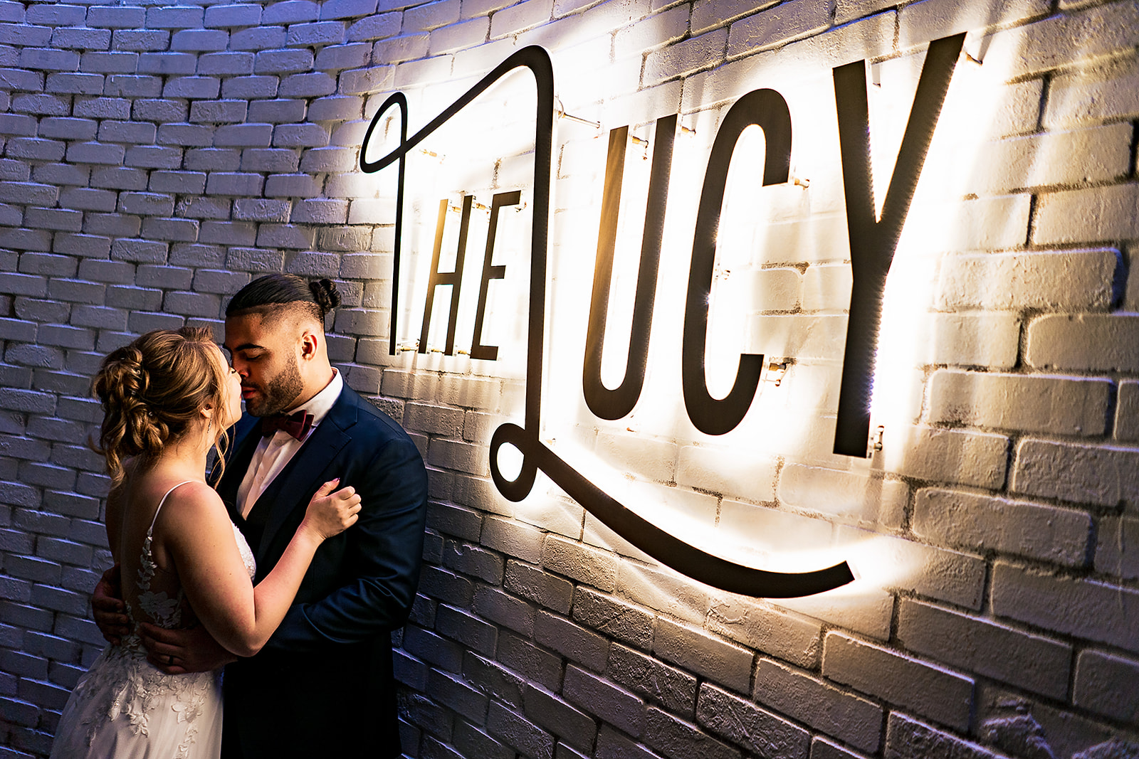 bridal portrait of couple kissing under the Lucy sign. 