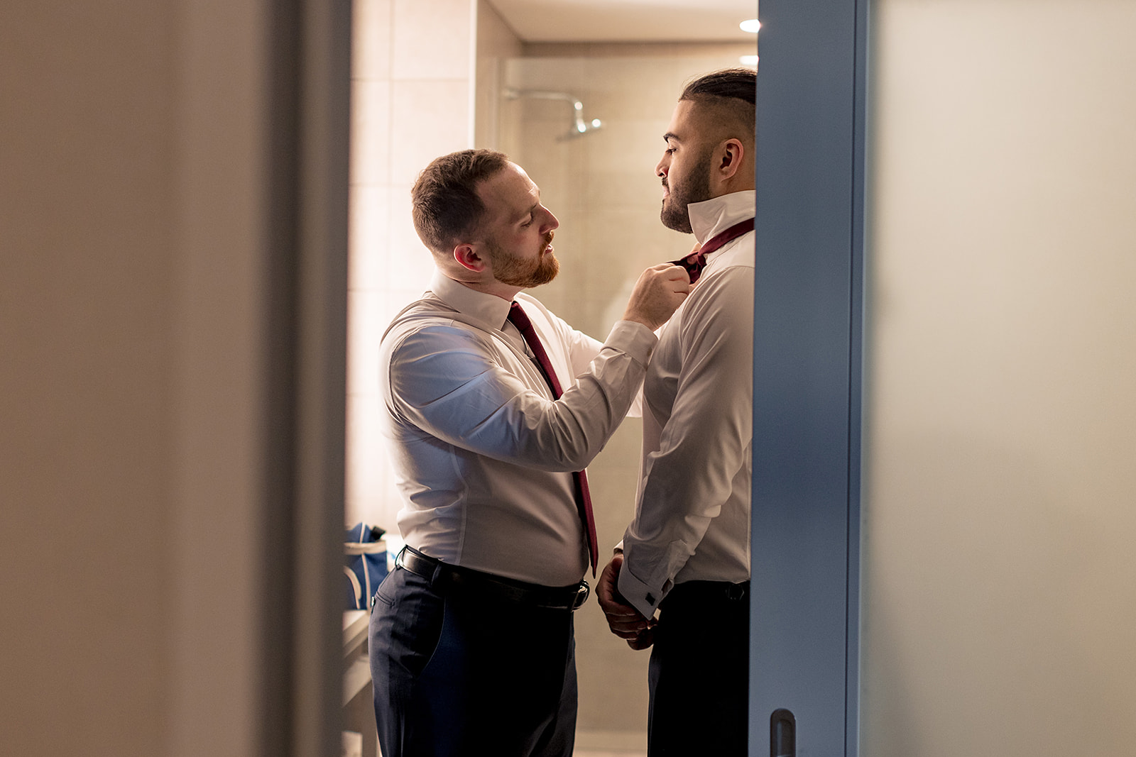 groomsman helping groom put on his tie for his Cambria hotel wedding