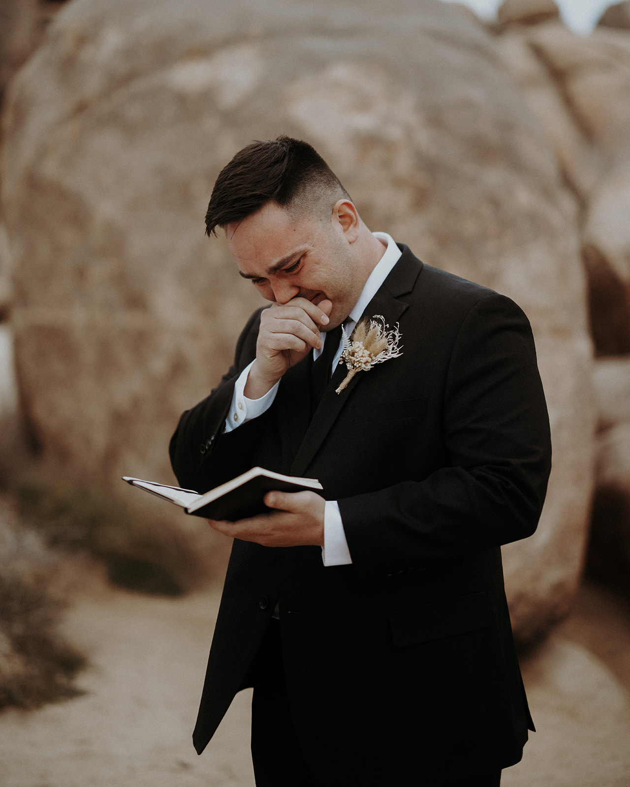 A groom crying reading his vows during his wedding at Quail Springs in Joshua Tree National Park .