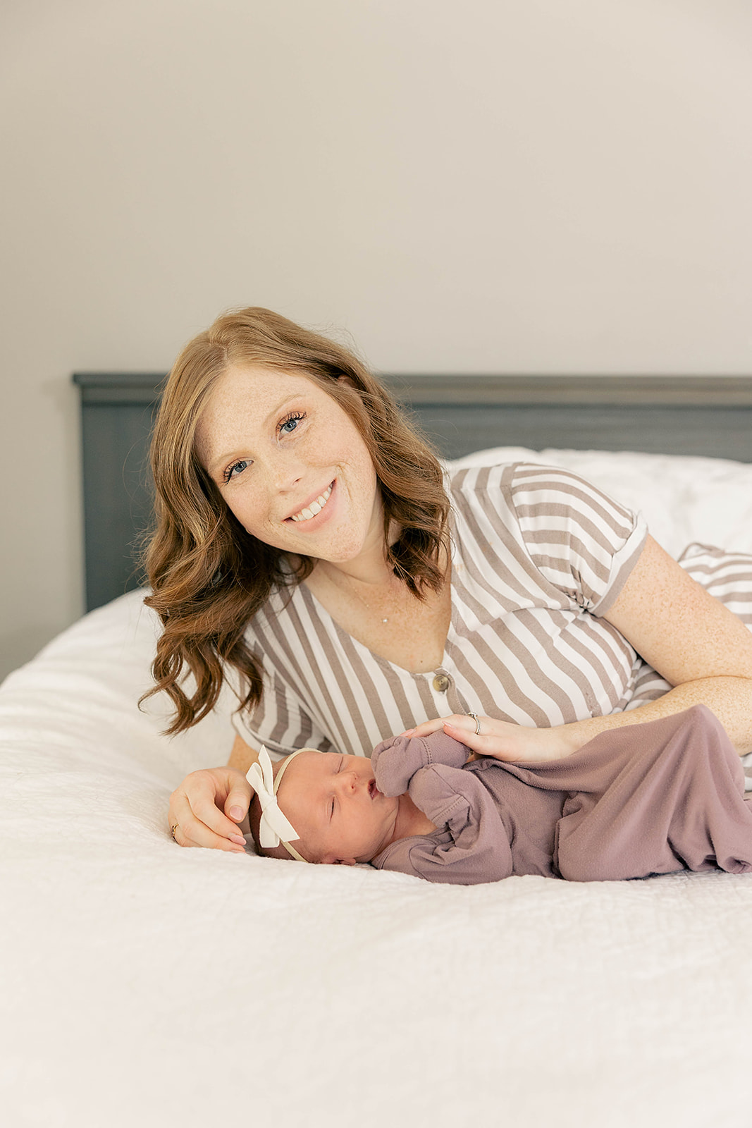 mom and newborn girl laying on white bedsheets