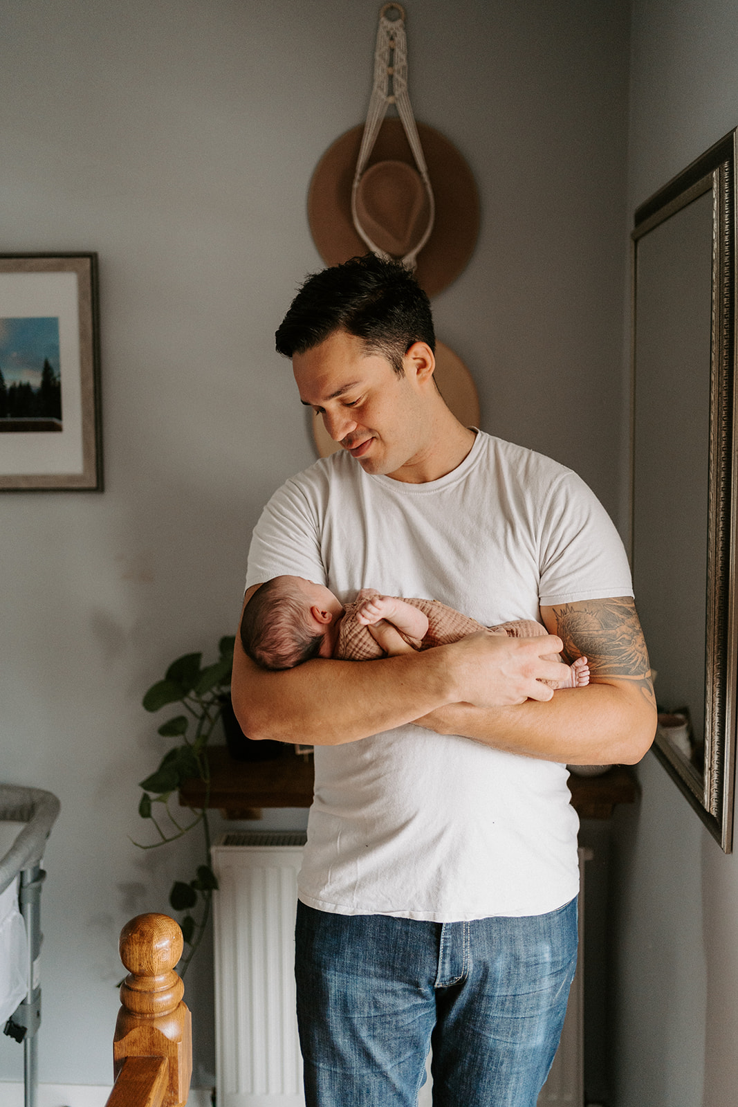 Father standing up holding newborn in arms while looking down at them