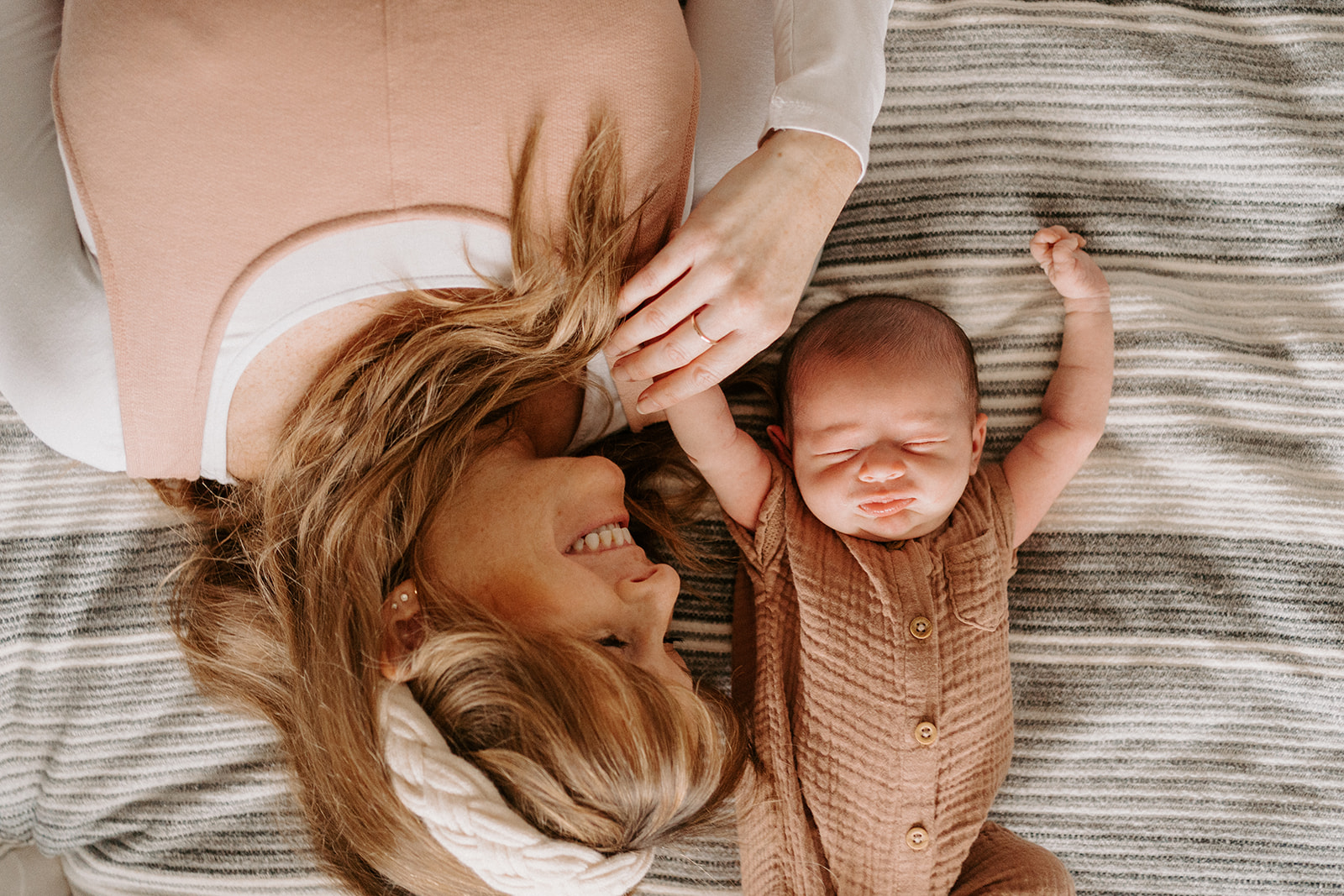 Mother smiling at newborn while holding newborns hand