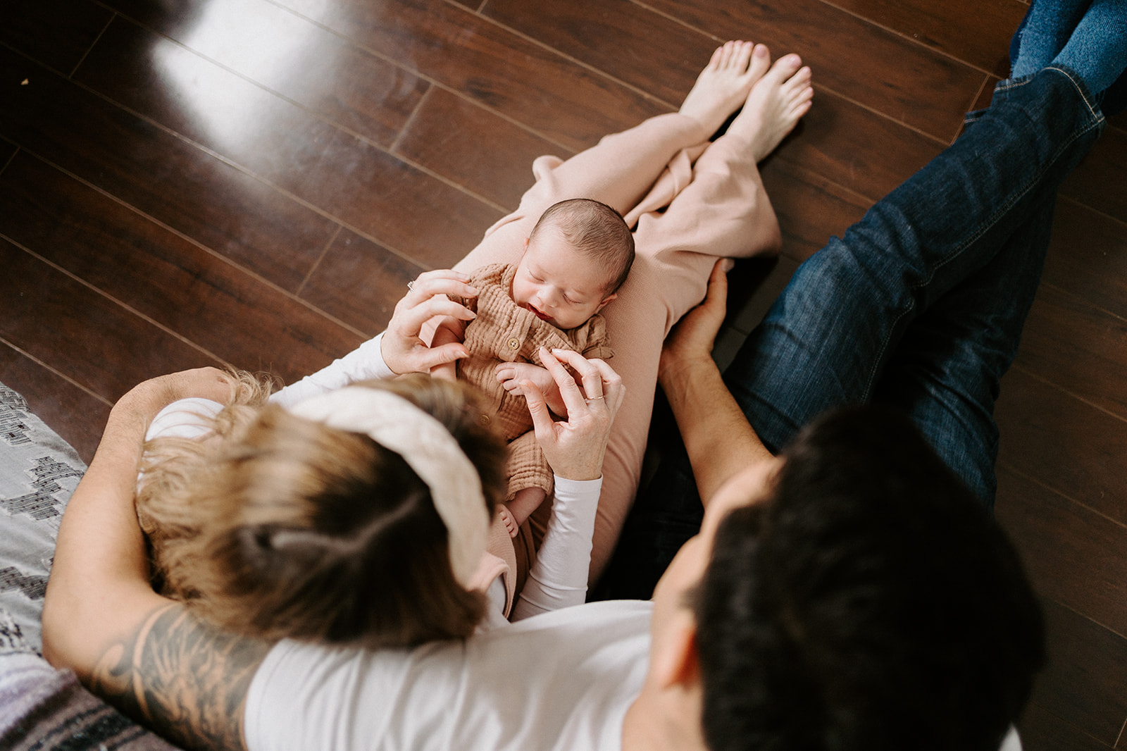 Over-head indoor family newborn session while both parents look at newborn