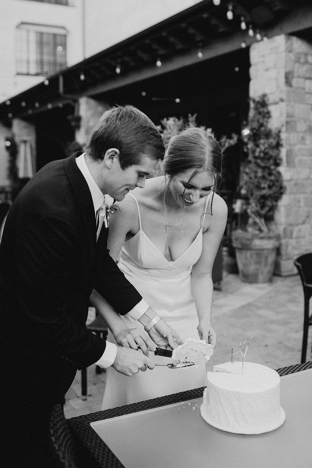 black and white photo of couple cutting a wedding cake