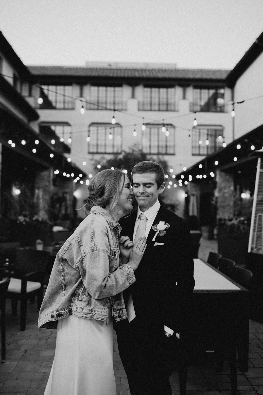 black and white photo of just married couple with string lights behind them