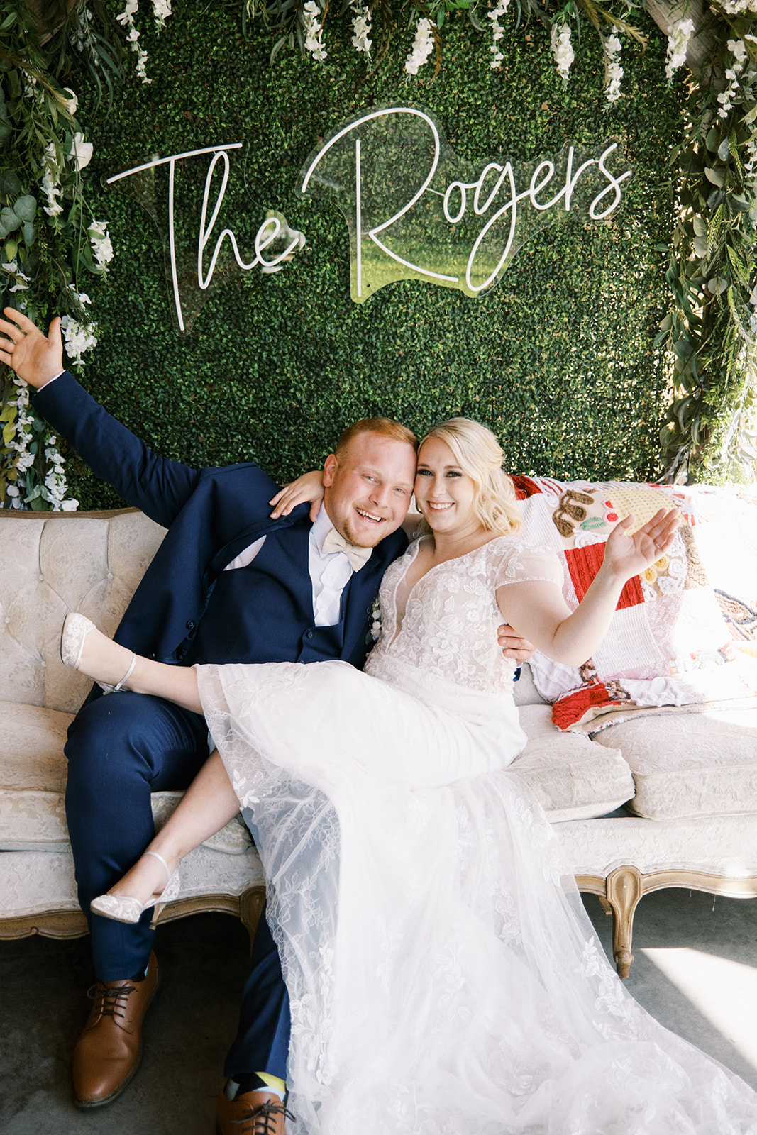The bride and groom sit on their sofa rental where their photobooth sits on their wedding day