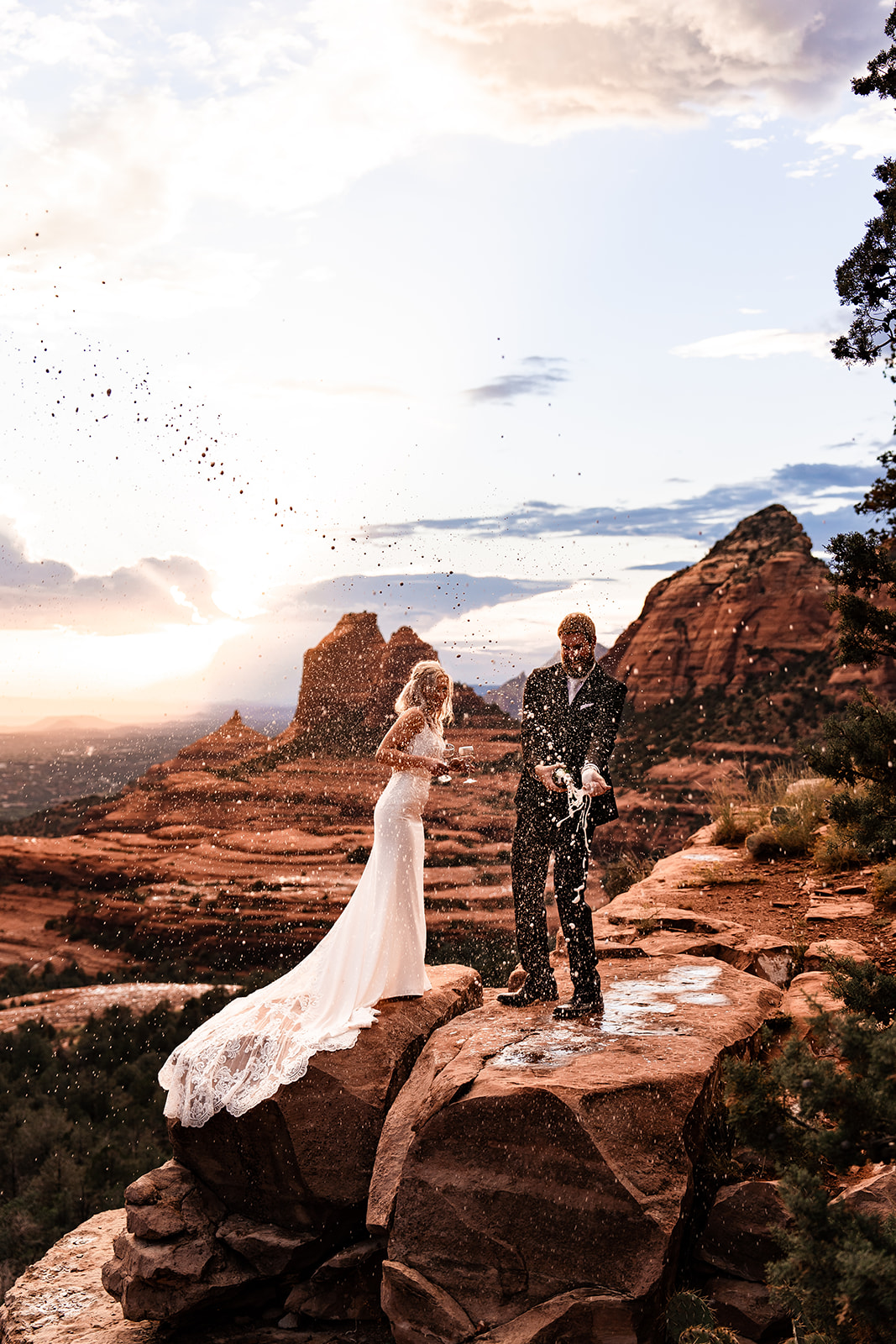 Elopement couple celebrating marriage at Merry Go Round Rock in Sedona with champagne bottle spray