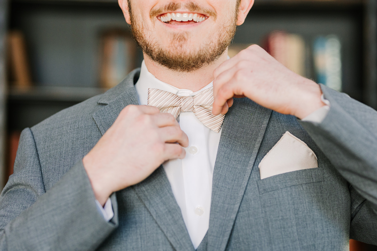 Groom tying his bowtie with a smile