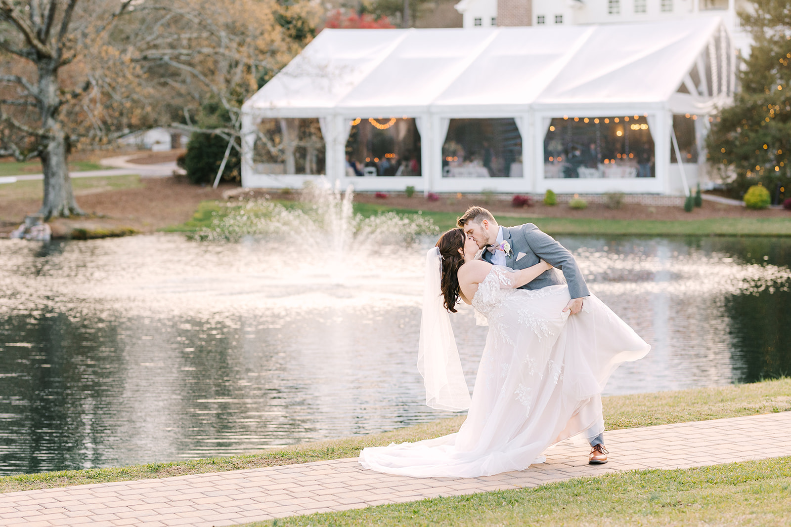 Wedding couple dipping in front of a pond for portraits at the Oaks at Salem