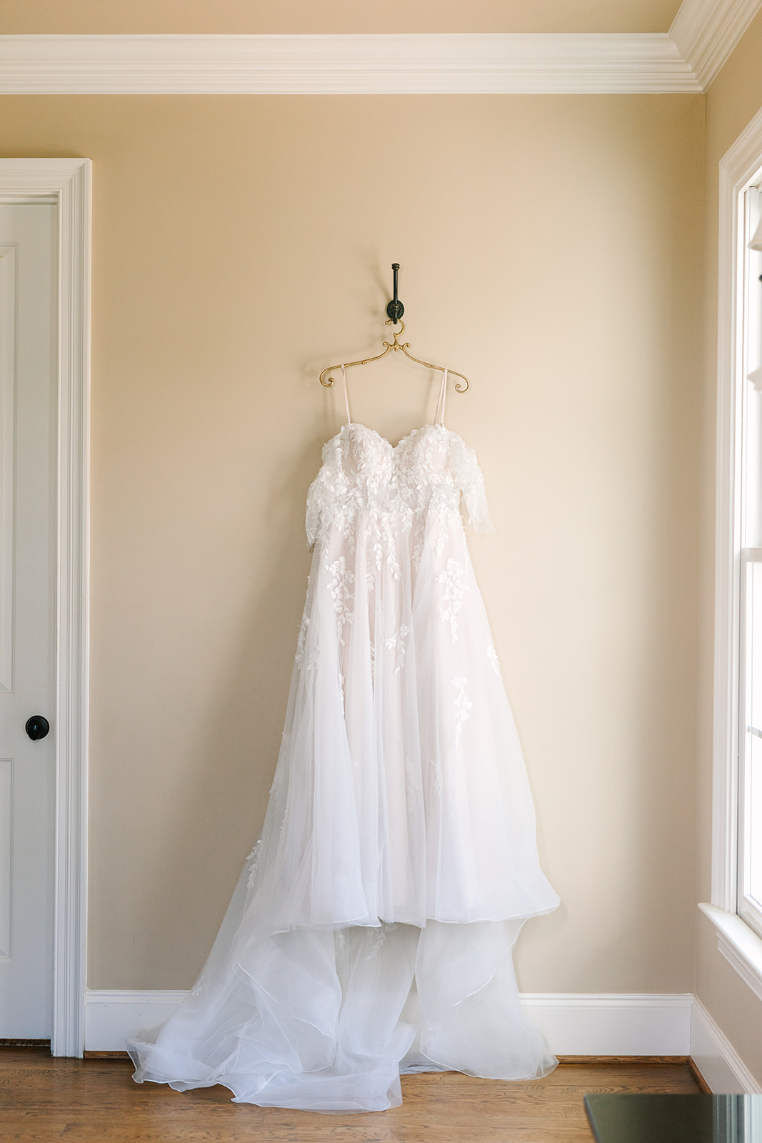 Wedding dress hanging in front of a window at the Oaks at Salem bridal suite