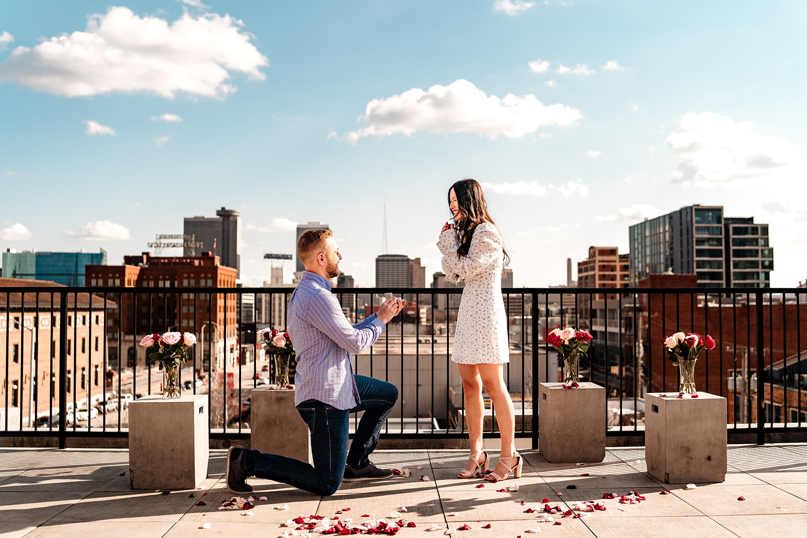 Couple getting engaged on Messenger Coffee rooftop with Kansas City skyline in background