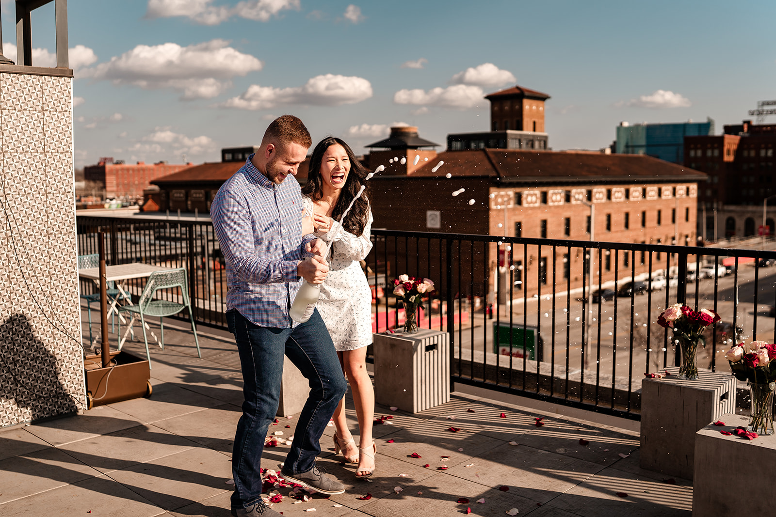 Engaged couple popping champagne on the roof of Messenger Coffee