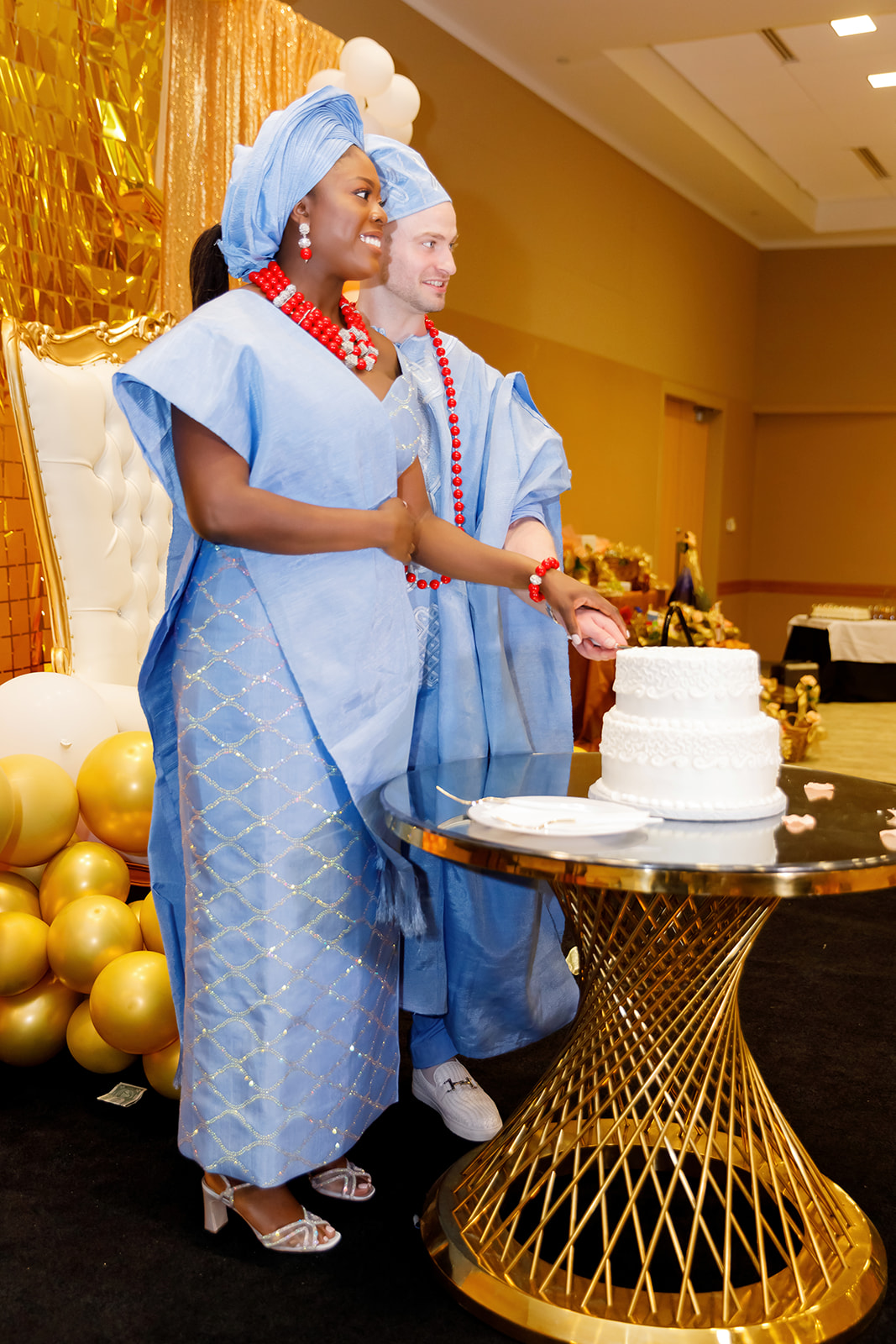 Bride and groom cutting cake during Nigerian and American traditional wedding at Truhlsen Campus Events Center at UNMC