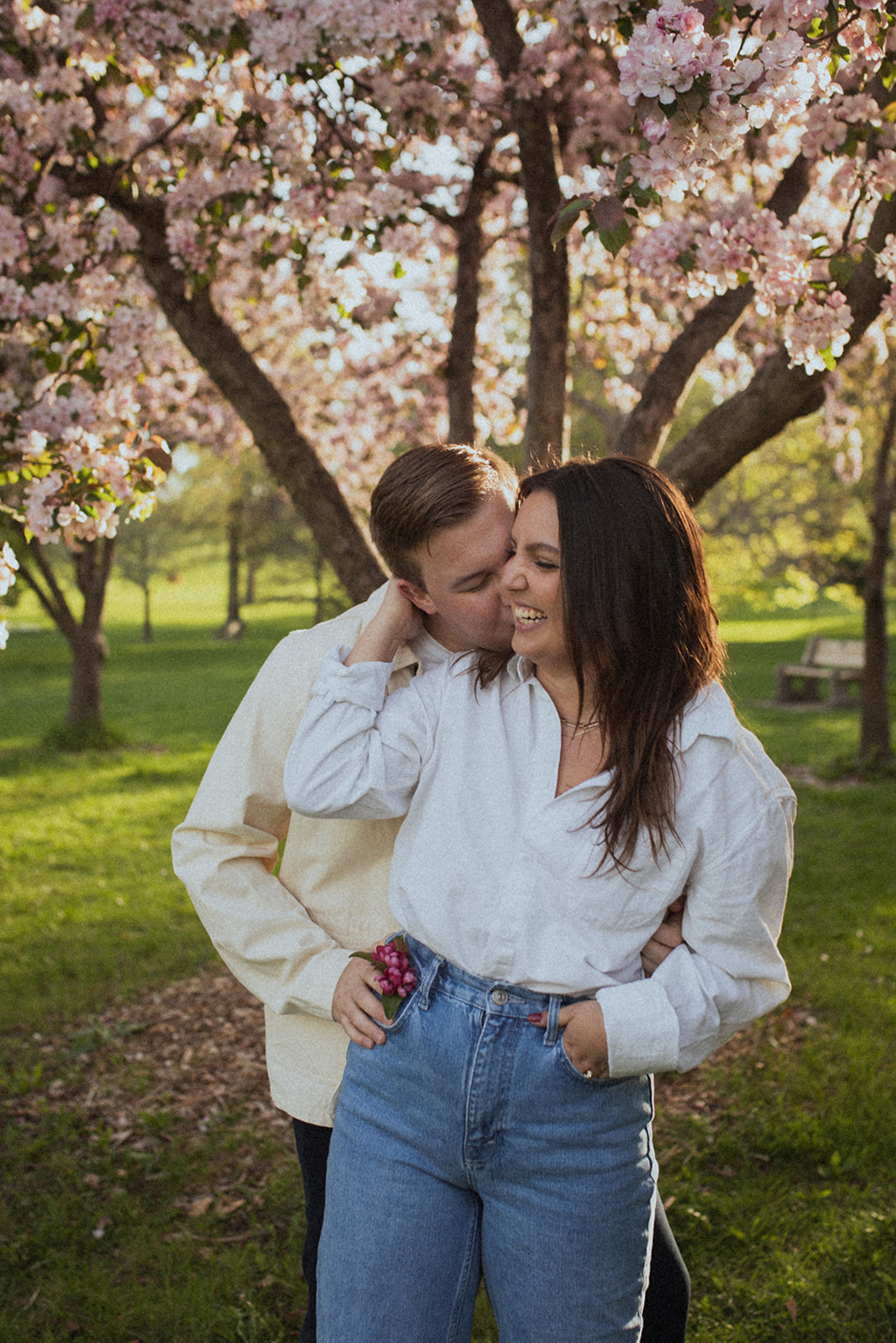 couple embracing each other and laughing together at sunrise under flowering trees