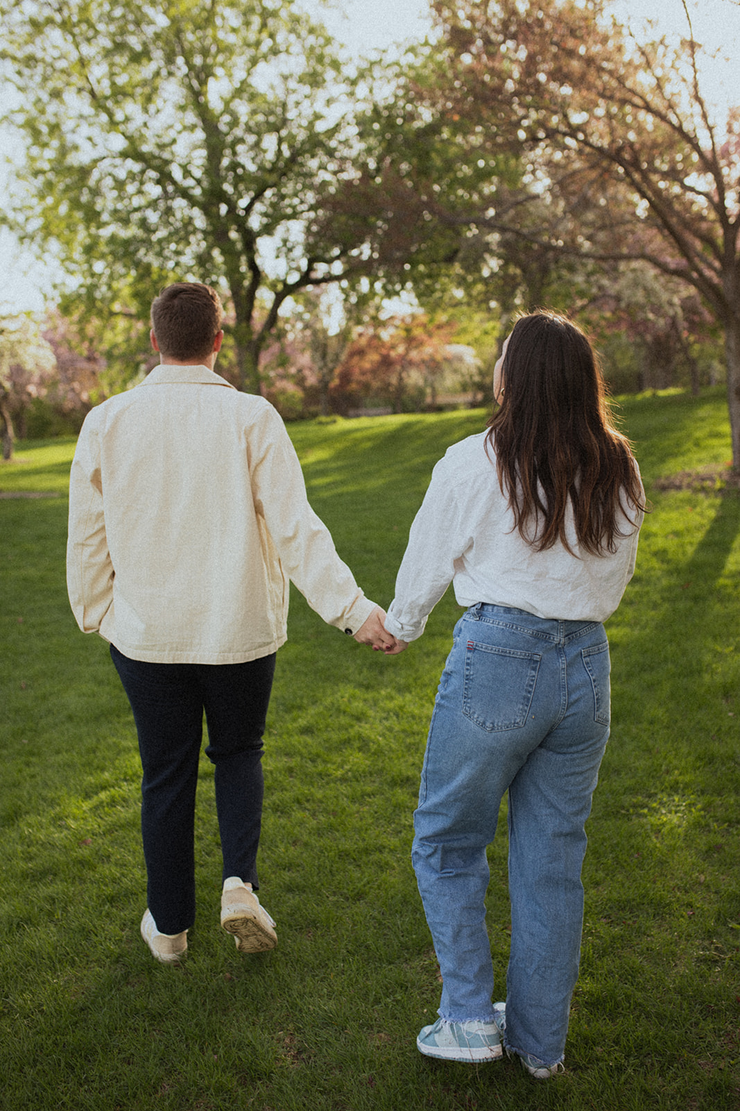 couple holding hands walking through Lyndale rose garden at sunrise