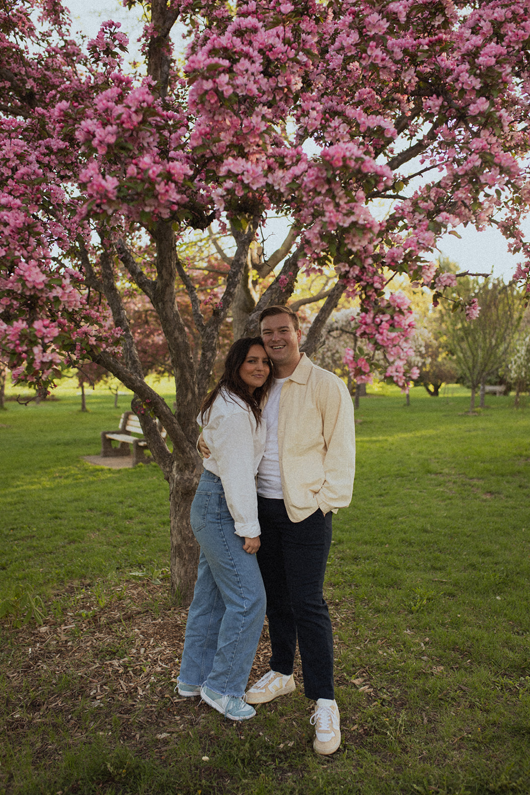 A couple standing together in front of pink blooming trees at sunrise