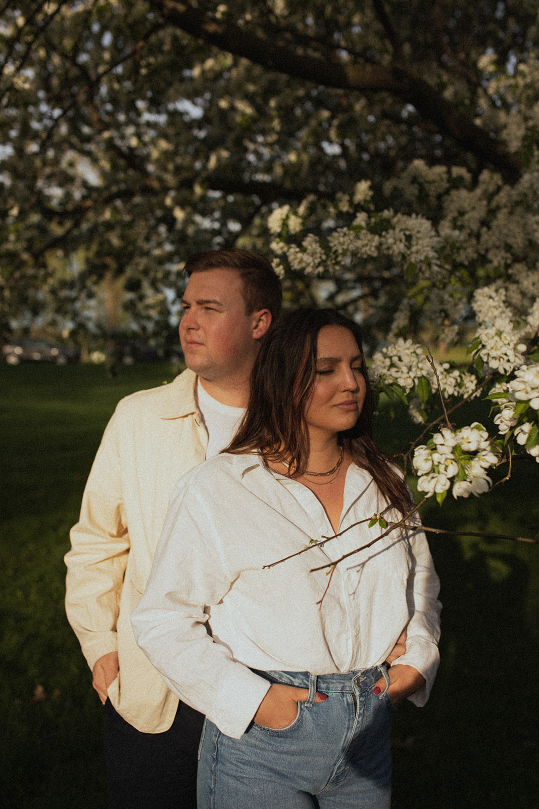 couple standing together under flowering trees in the sunlight during sunrise