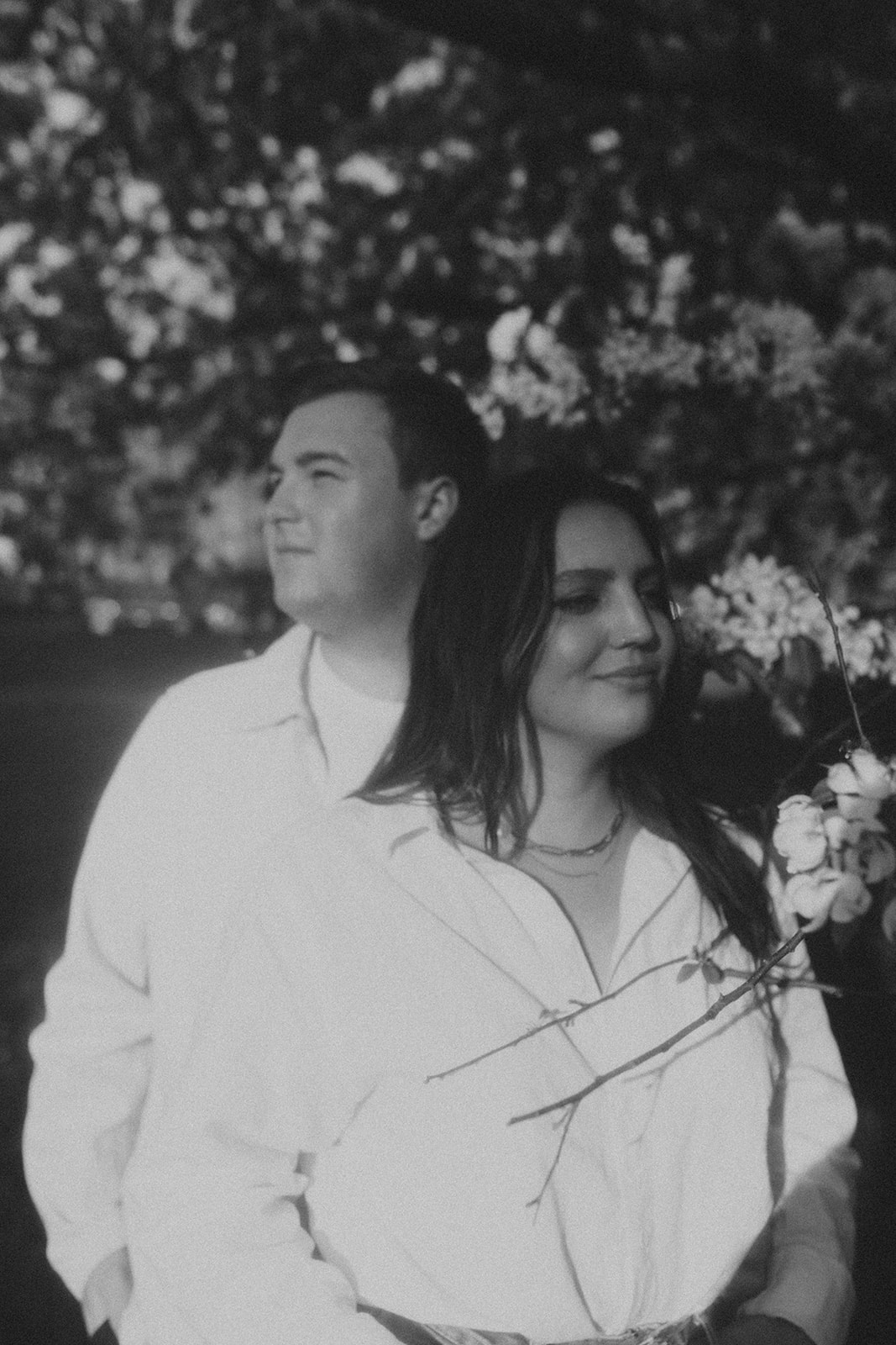 couple standing together under flowering trees in the sunlight during sunrise