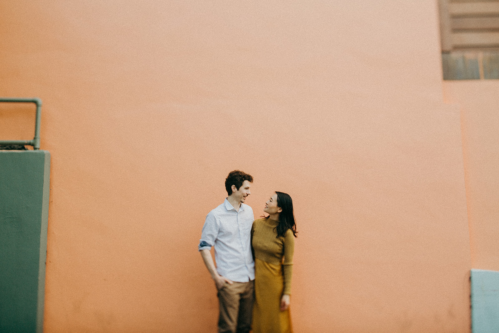 couple standing in front of coral colored building