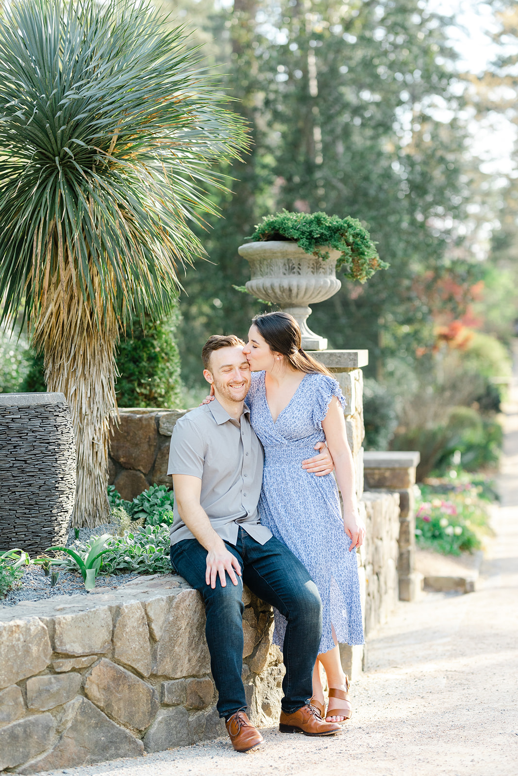 Couple at Duke Gardens in the spring sitting against a stone wall