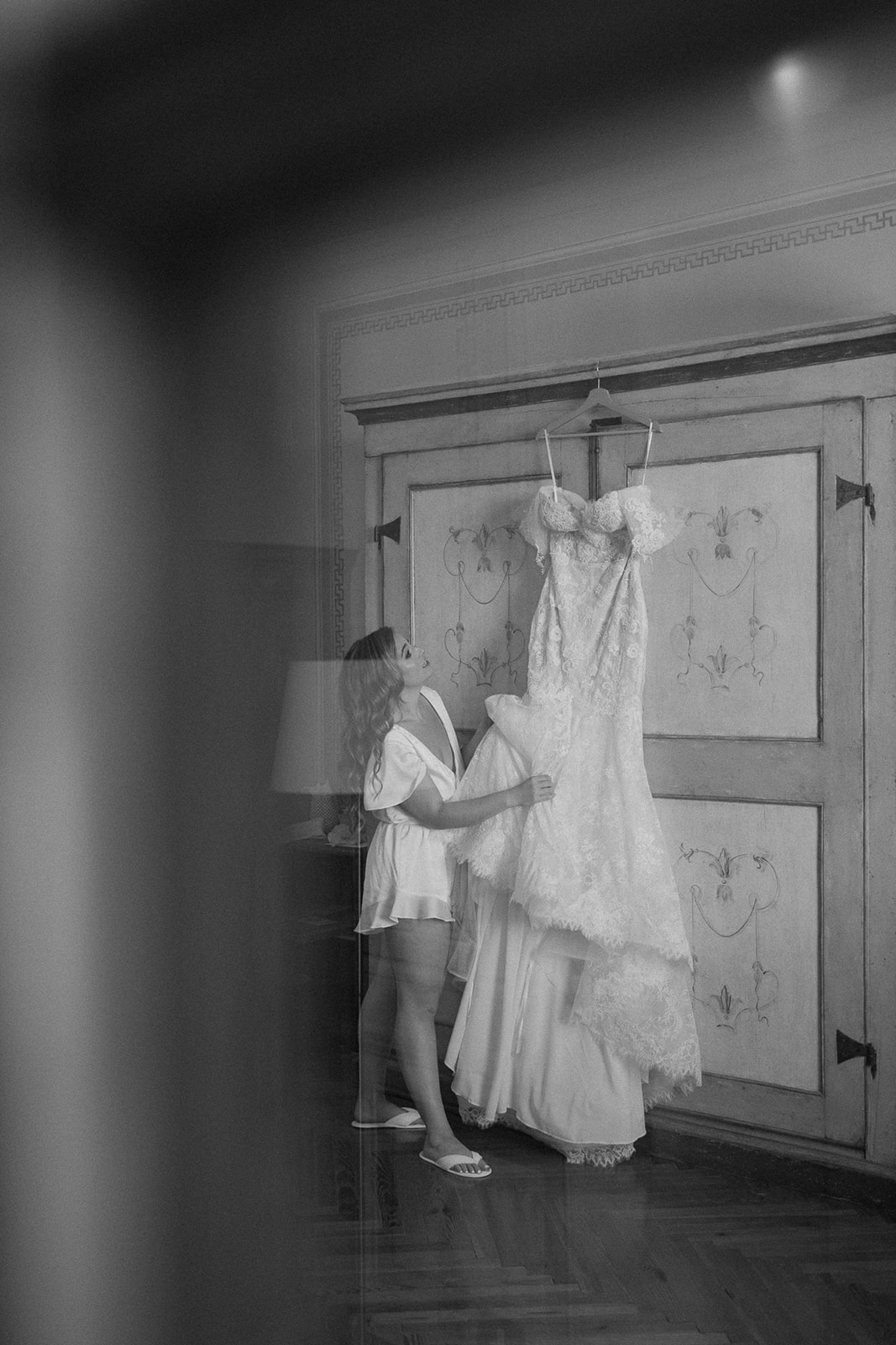 bride holds wedding dress hanging on wall