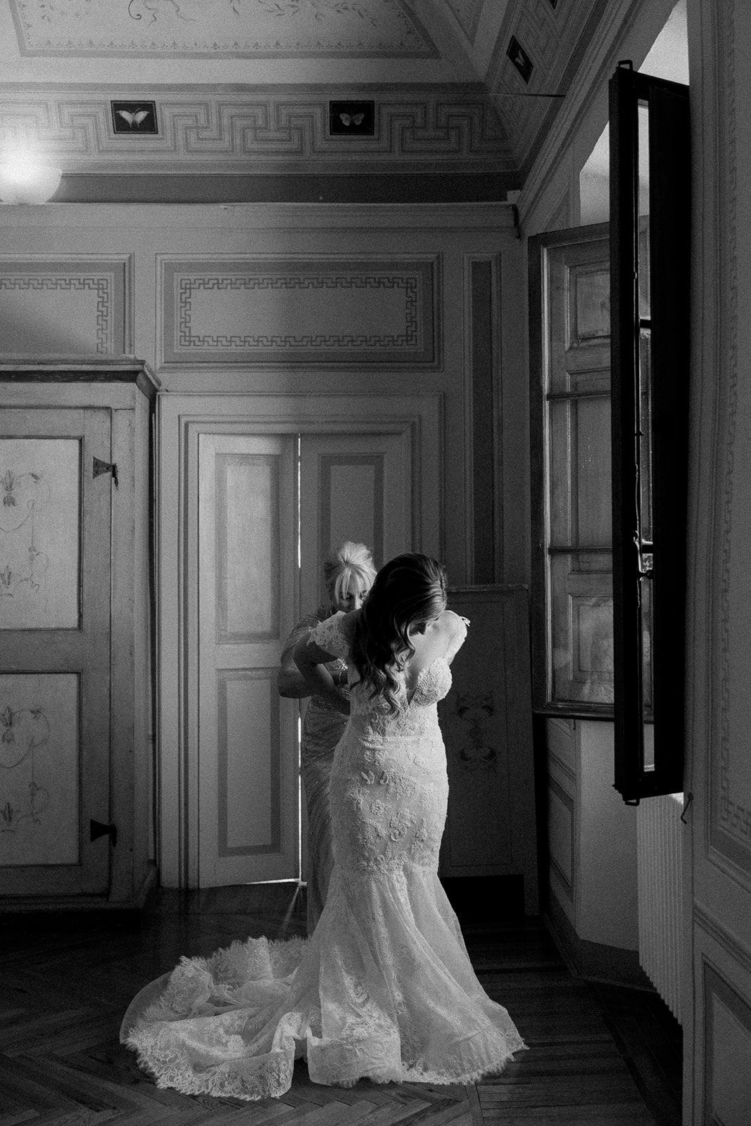 bride puts on wedding dress in window light