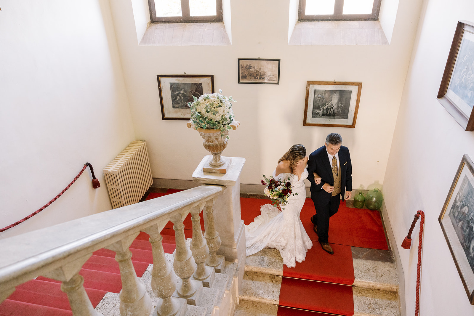 bride and man walk down red carpeted steps