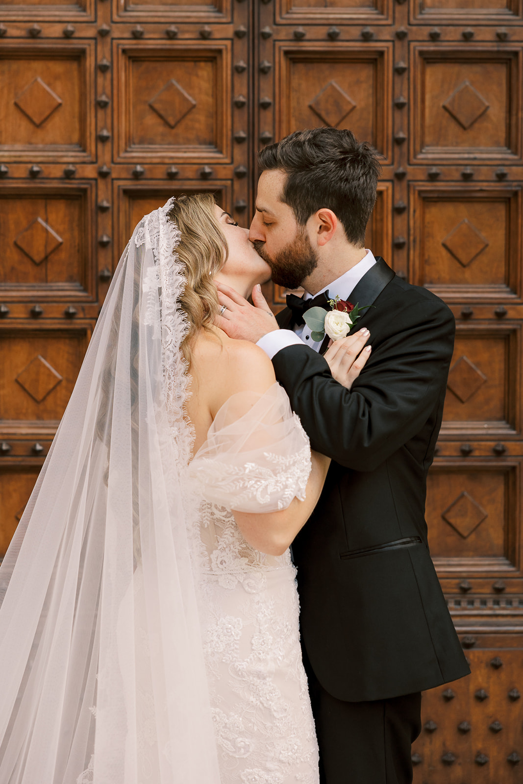 bride and groom kiss together in front of grand Italian doors 