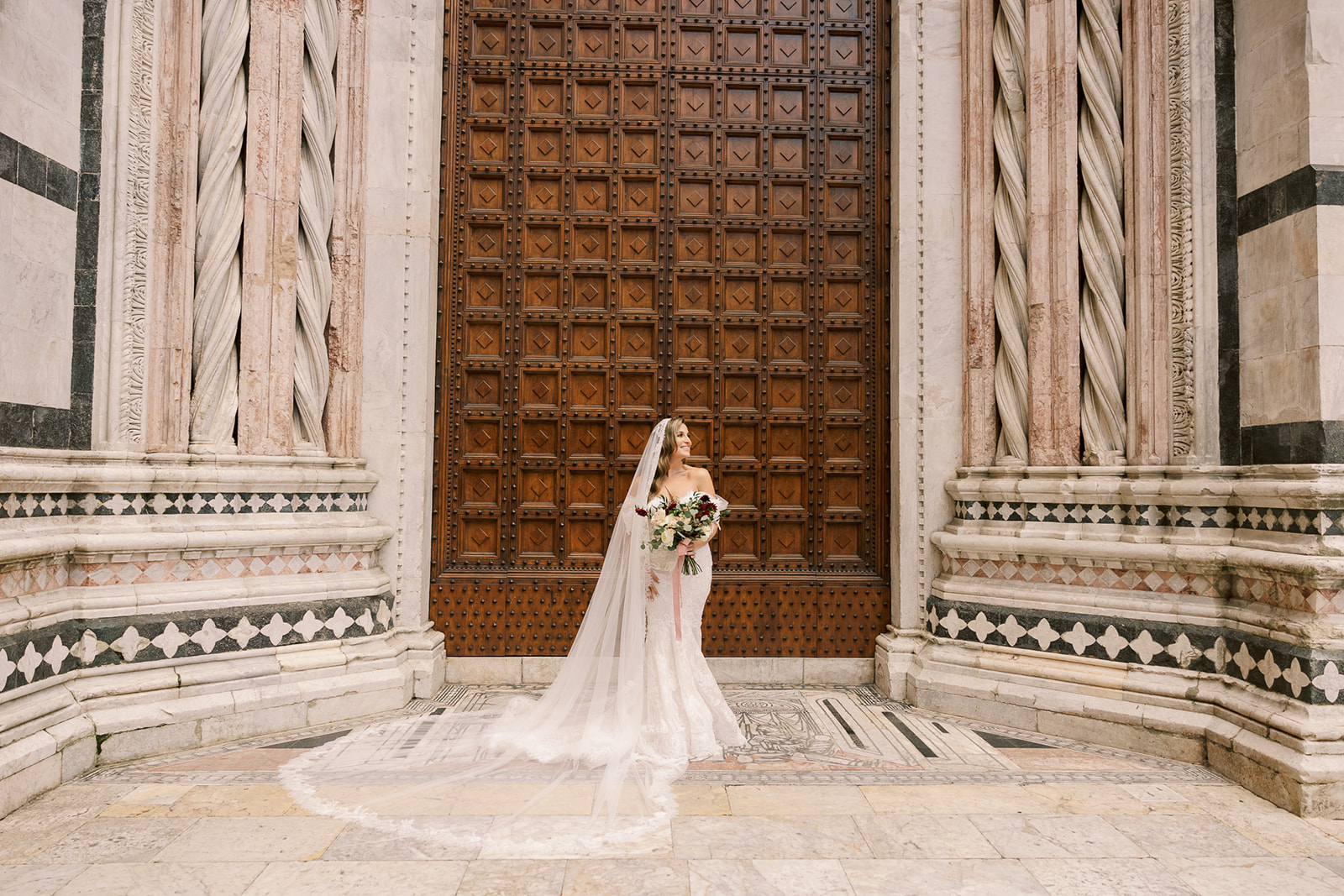 bride pose together in front of grand Italian doors 