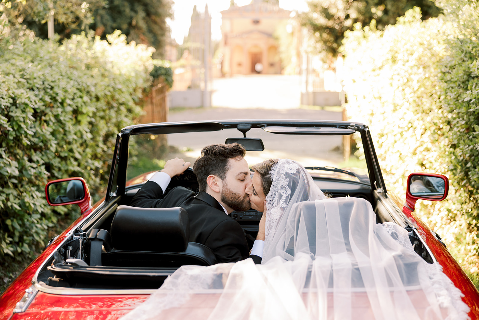 bride and groom kiss in red sports car