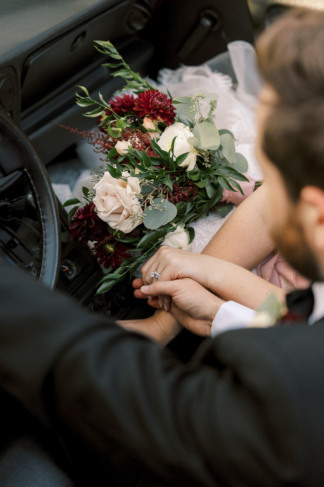 bride and groom hold hands with bouquet between them