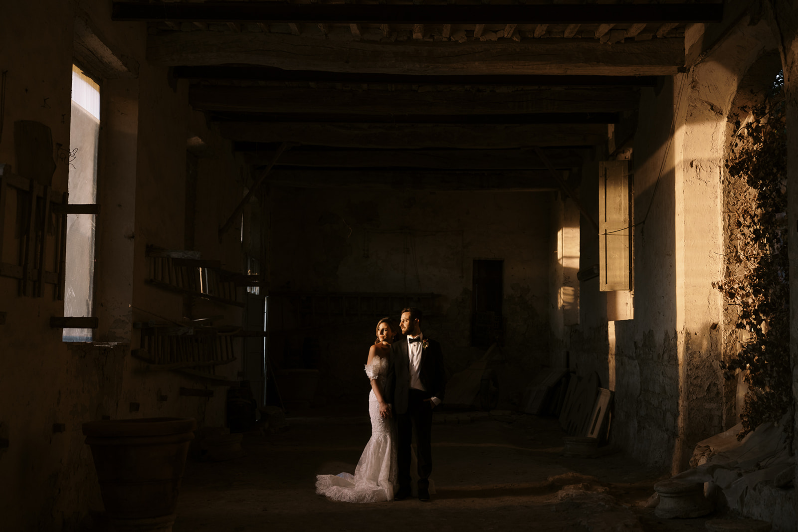 bride and groom stand in ruins with harsh light