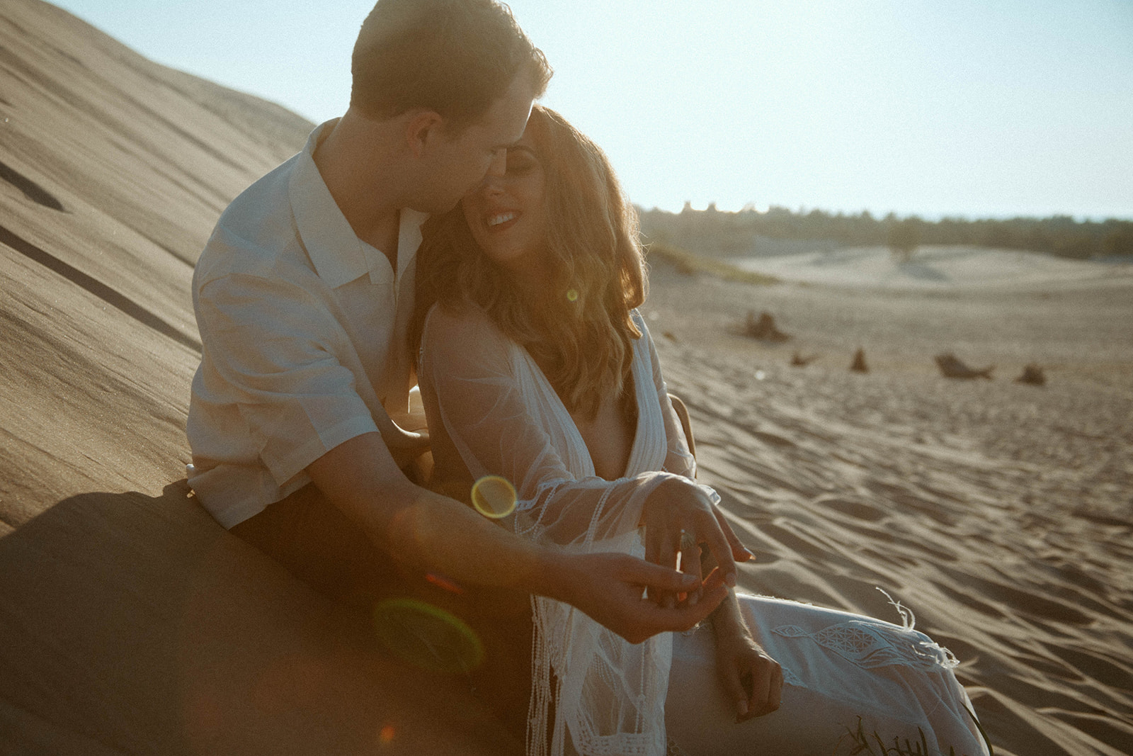 A couple who did bridal photos at the sand dunes share an intimate moment together.