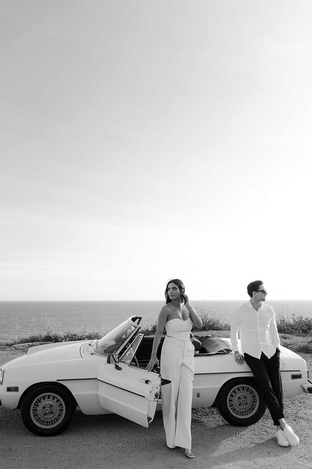 A couple poses in front of a vintage car in Malibu.