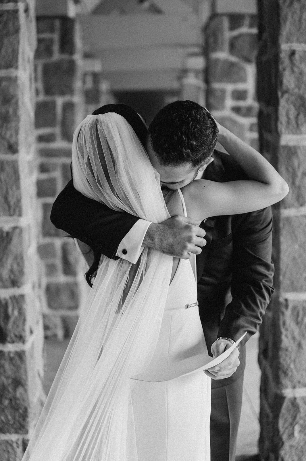 Black and white photo of bride and groom hugging during their first look before the ceremony