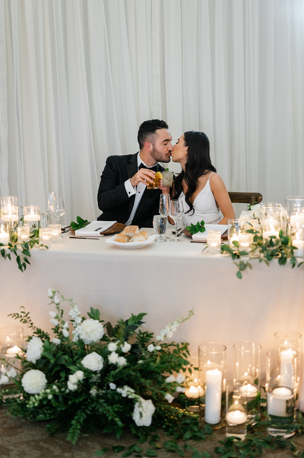 Bride and groom kissing at the sweetheart table at their wedding reception