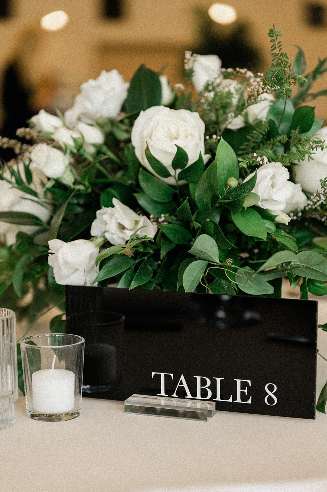 White roses and greenery centerpieces and table number 