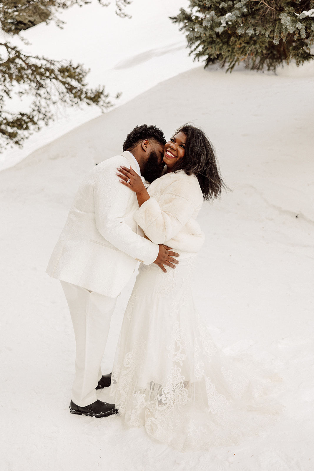 Frances and Peterson kissing eachother smiling during their snowy anniversary session 