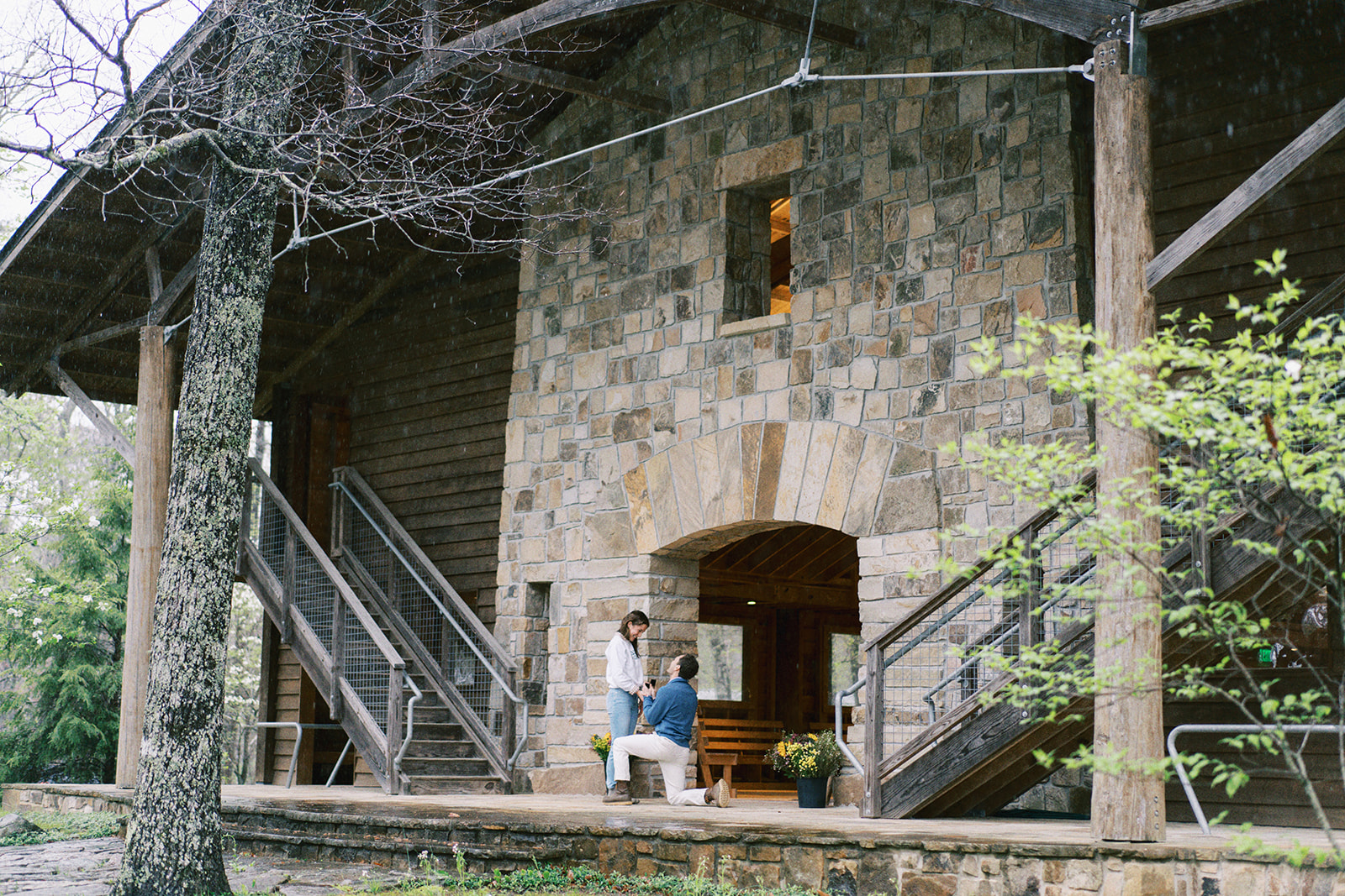 A young man surprises his girlfriend with a proposal in front of the beautiful gym at Camp DeSoto in Mentone, Alabama