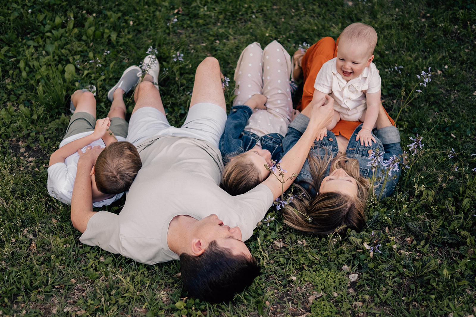 A family lays together at their outdoor family session at a park