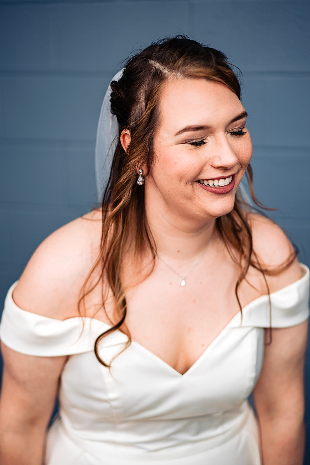 bride laughing with blue wall behind her