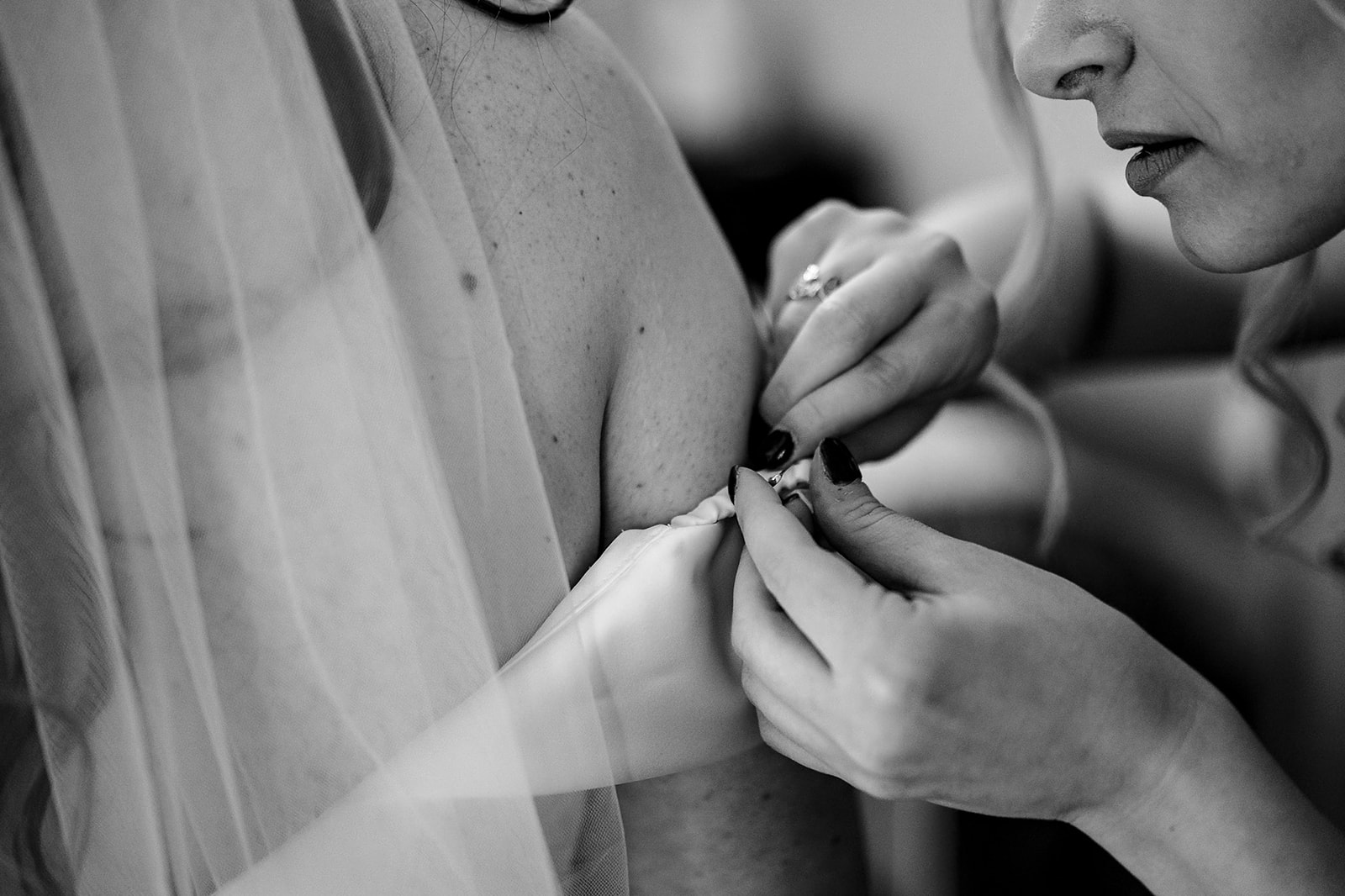 woman's face focused as she fixes a brides dress