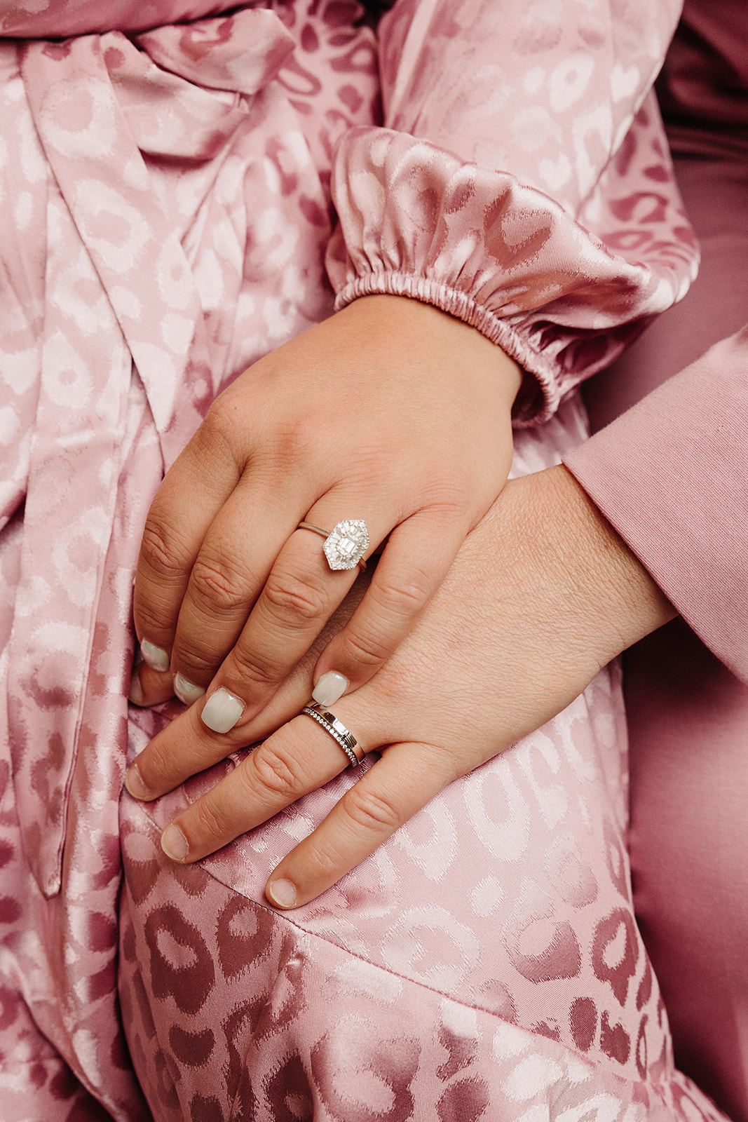 Women holding hands showing their vintage engagement rings during their city engagement session